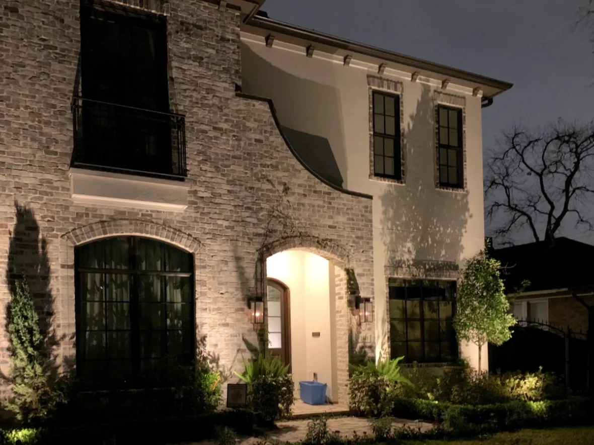 Arched stone entry lit so the doorway is the brightest point of the elevation