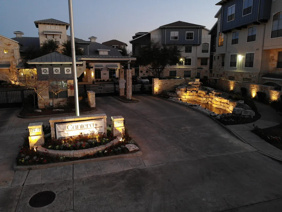 Entrance drive of a commercial property with lit monument signage and building facades