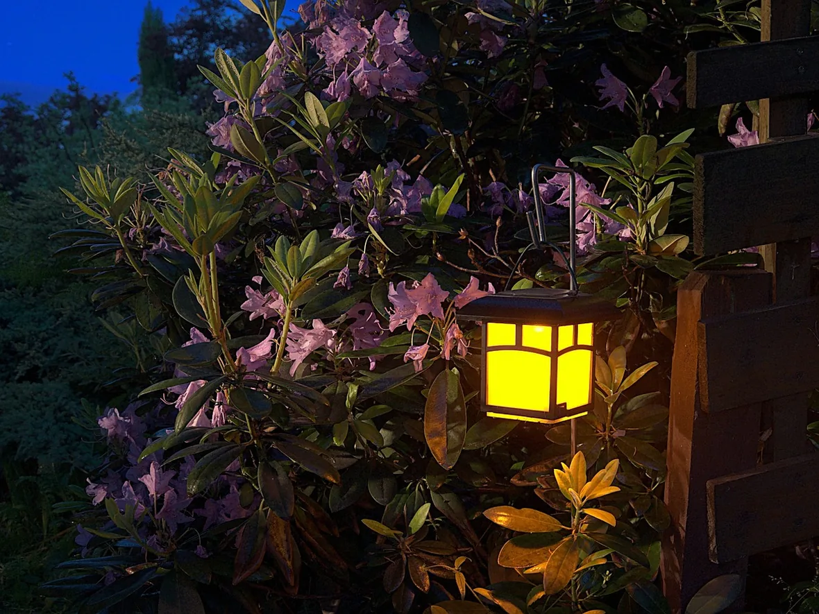 Garden lantern and planting beside a seating area, lighting the space from the side rather than overhead
